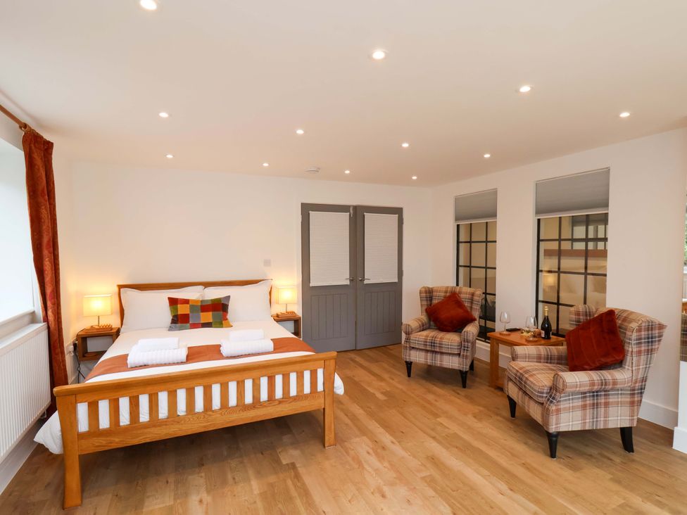 A bedroom with a bed and armchairs at Sandy Nook in Redcar