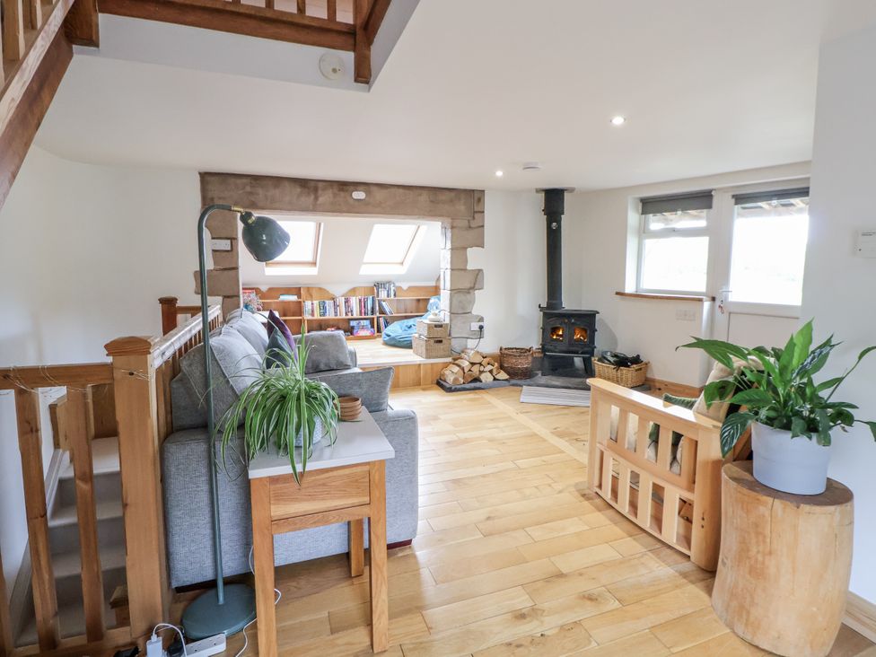 A living room with a wood stove and bookshelves at The Hayloft in Bodelwyddan