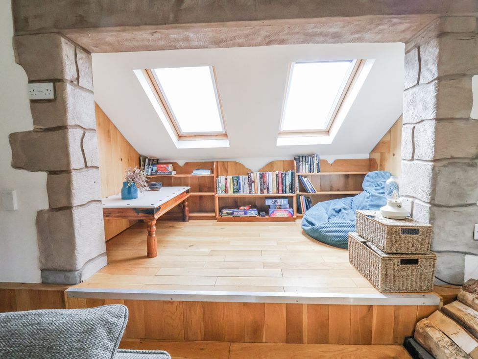 A snug with a bookshelf and table at The Hayloft in Bodelwyddan