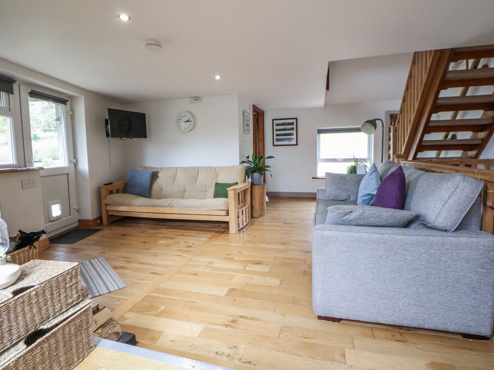 A living room with a sofa, futon, and television at The Hayloft in Bodelwyddan