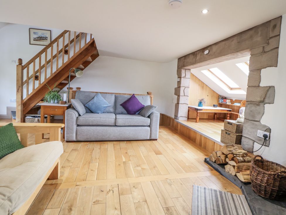 A living room with a sofa and staircase at The Hayloft in Bodelwyddan