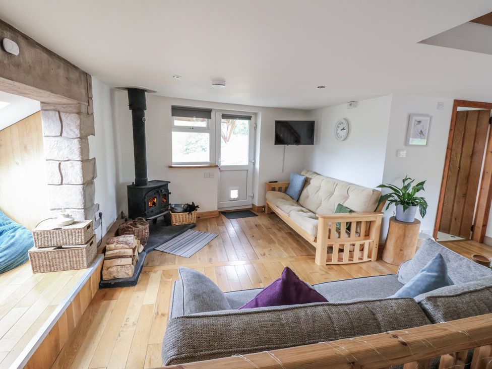 A living room with a wood stove and a sofa at The Hayloft in Bodelwyddan