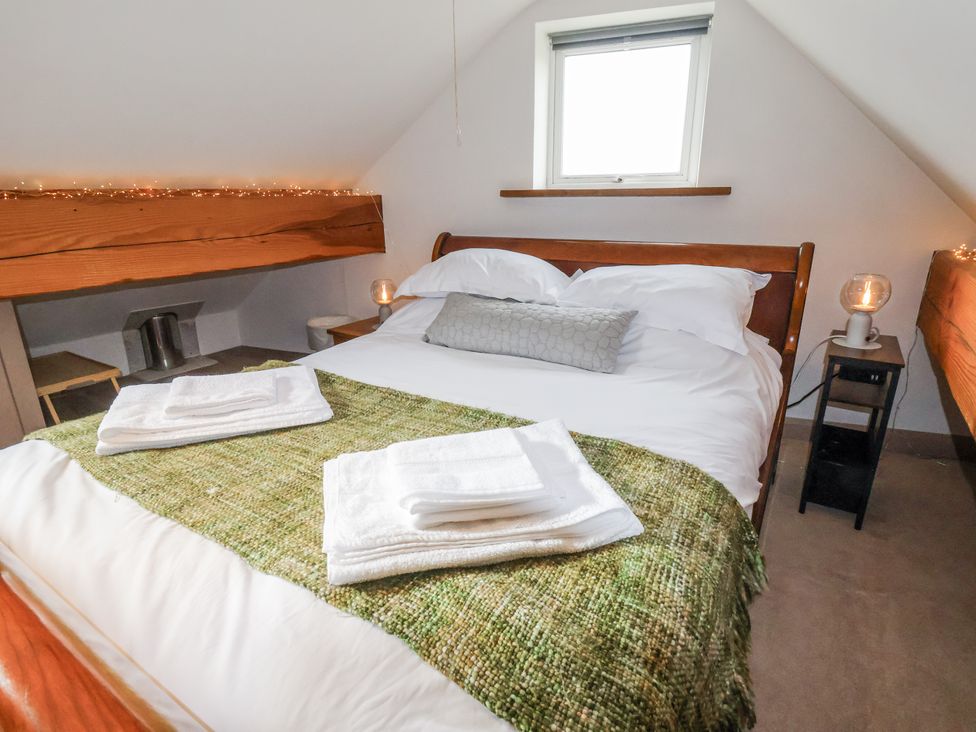 A bedroom with a bed and bedside table at The Hayloft in Bodelwyddan