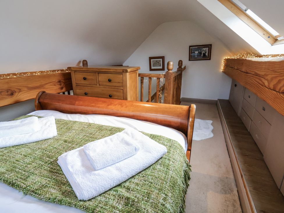 A bedroom with a bed and a dresser at The Hayloft in Bodelwyddan