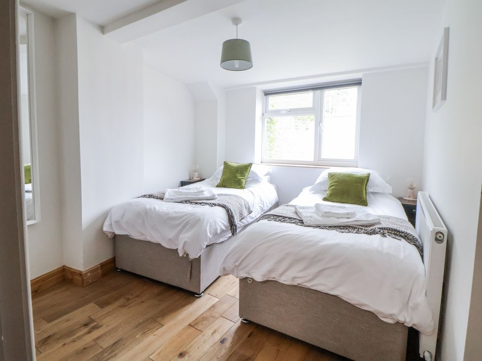 A bedroom with two single beds and a window at The Hayloft in Bodelwyddan