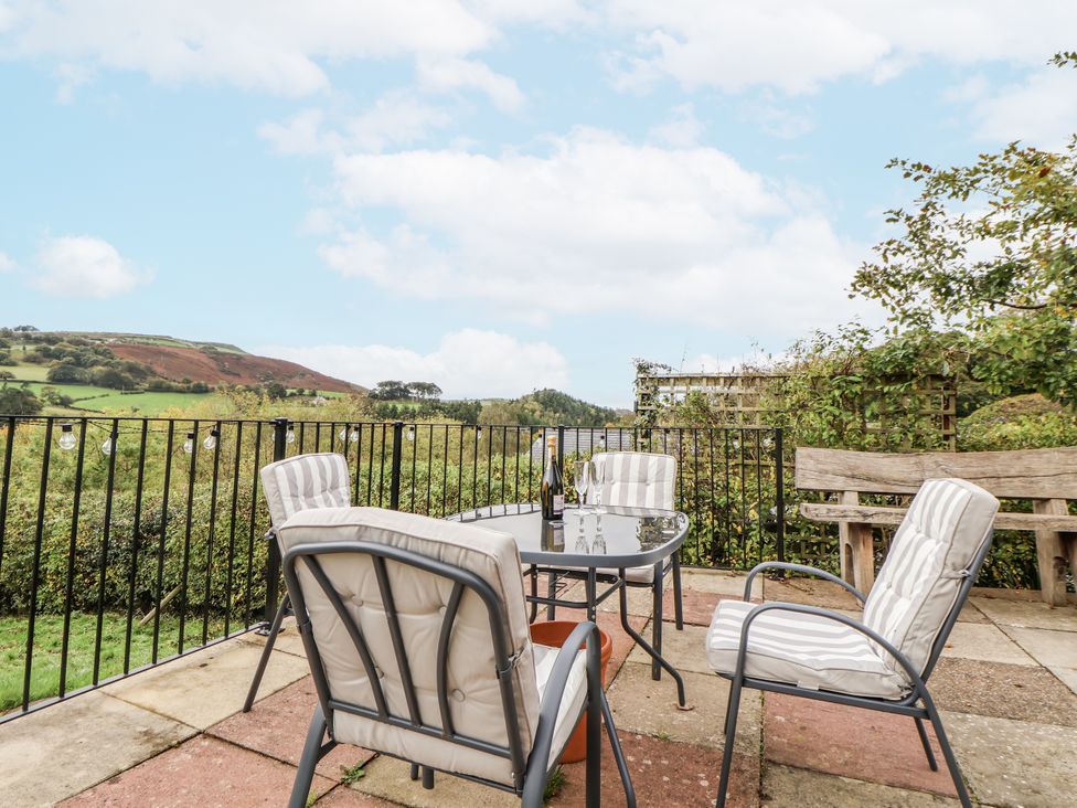 An outdoor seating area with a table and chairs overlooking the landscape at The Hayloft in Bodelwyddan