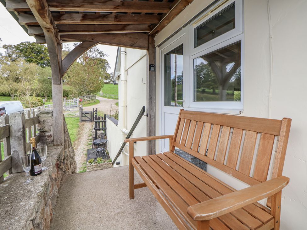 An outdoor seating area with a wooden bench and champagne at The Hayloft in Bodelwyddan