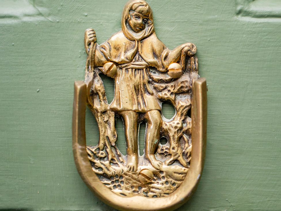 A brass door knocker depicting a figure with a fishing theme