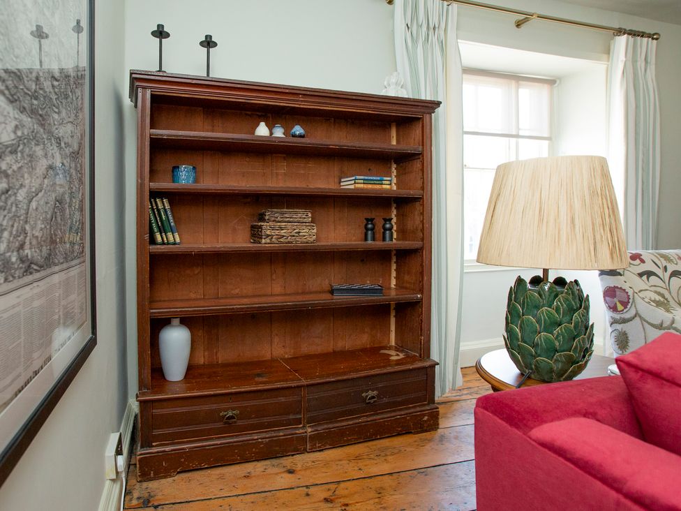 A bookcase with books and decorative items in a living room at Apartment 2, 86 Dyer Street in Cirencester