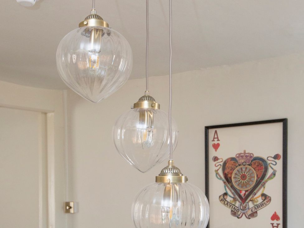 A hanging light fixture with three bulbs and wall art at Apartment 2, 86 Dyer Street Cirencester