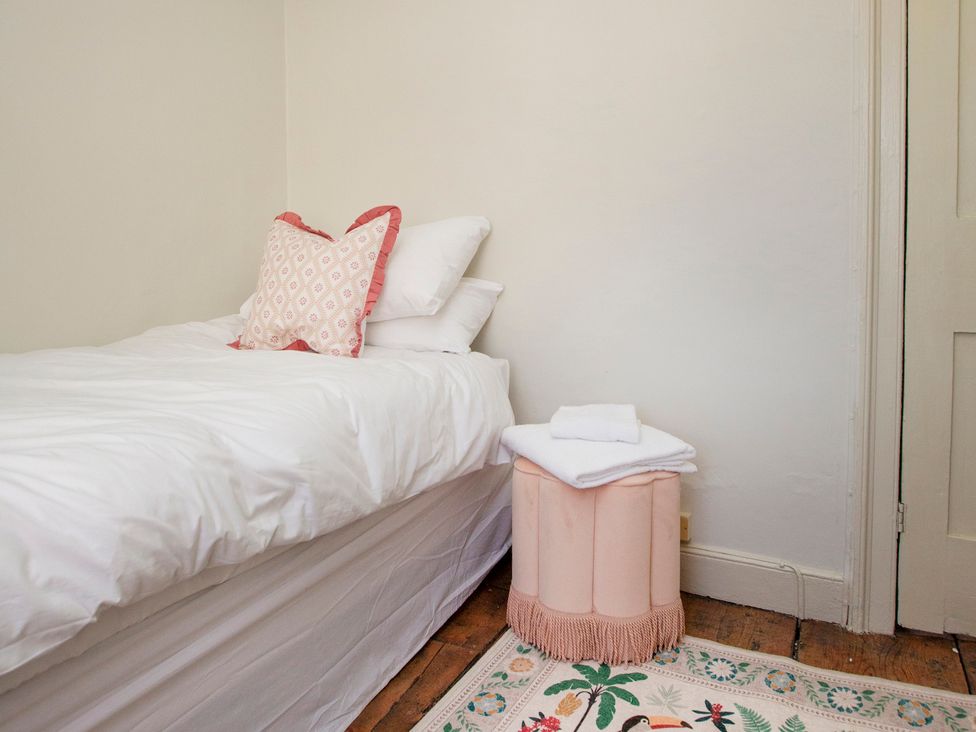 A bedroom with a bed and decorative stool at Apartment 2, 86 Dyer Street Cirencester