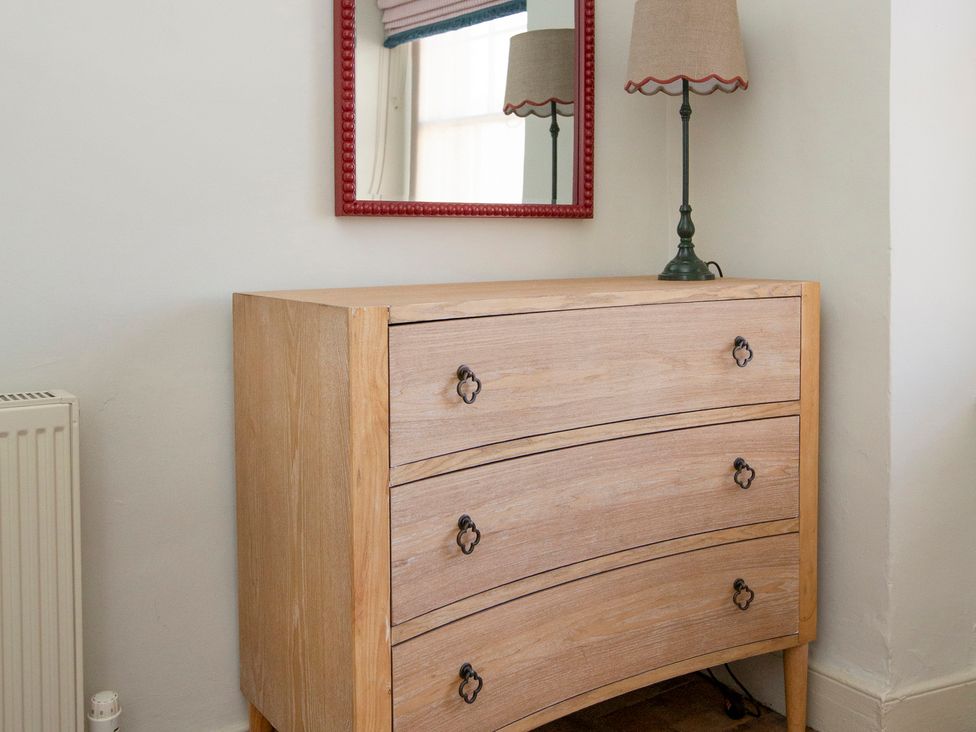 A dresser with a mirror and lamp in a bedroom at Apartment 2, 86 Dyer Street, Cirencester
