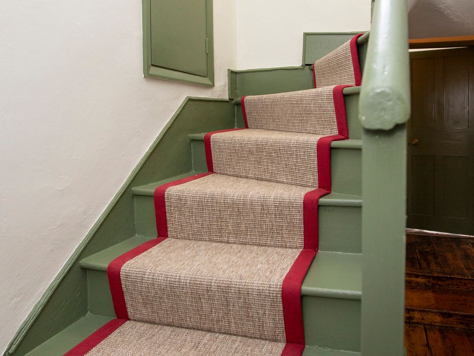 A staircase with a carpet runner at Apartment 2, 86 Dyer Street Cirencester