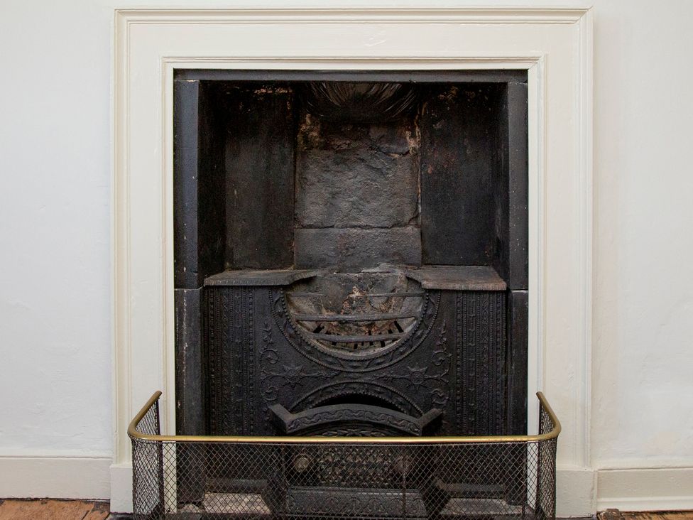 A fireplace with a metal grate at Apartment 2, 86 Dyer Street Cirencester