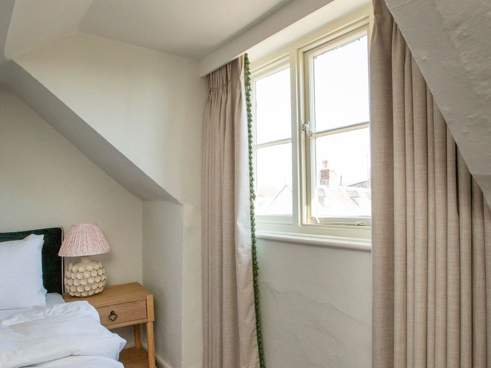 A bedroom with a bed, lamp, and window at Apartment 2, 86 Dyer Street Cirencester