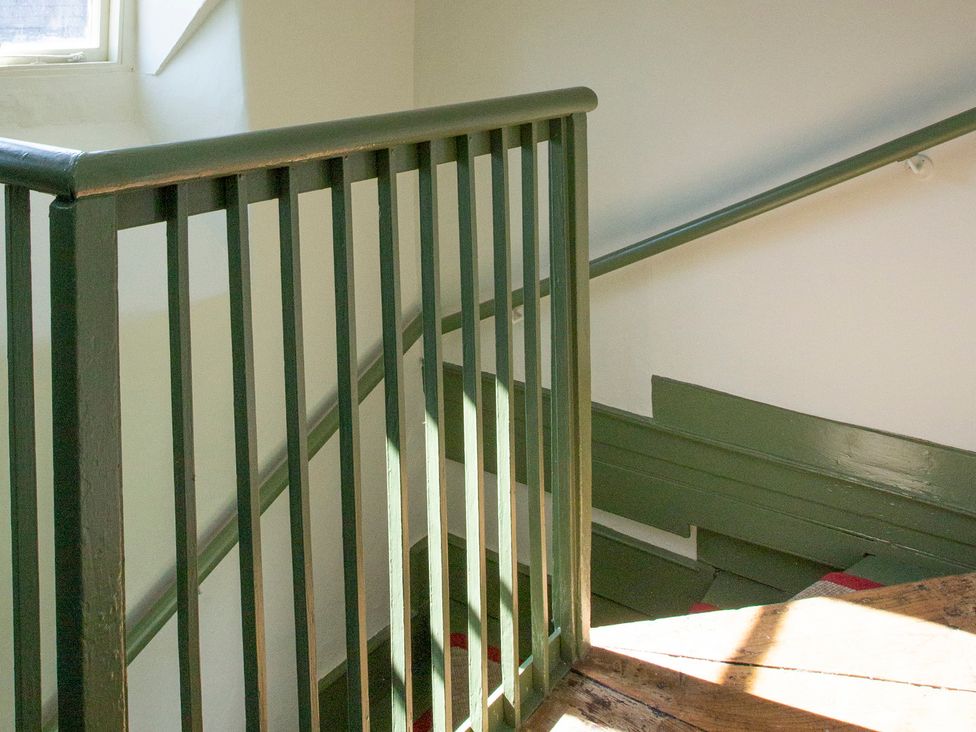 A staircase with a railing and wooden steps at Apartment 2, 86 Dyer Street Cirencester