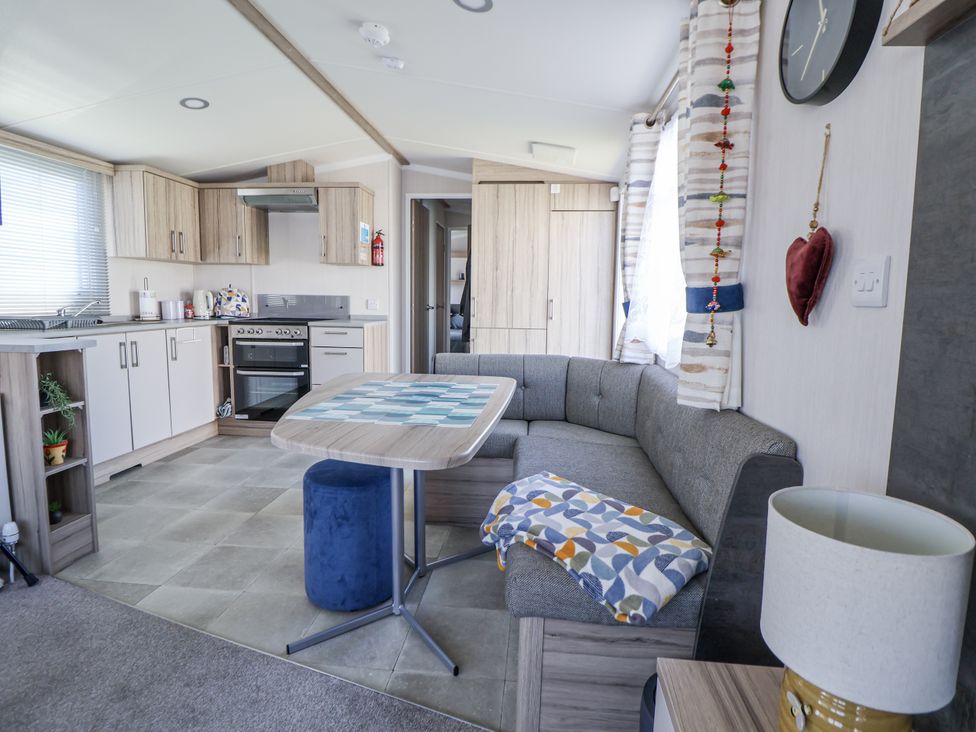 A living room with a kitchen area and sofa at V9 Ty Mawr Holiday Park