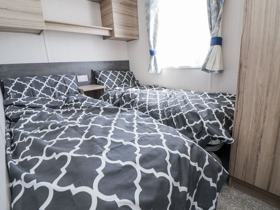 A bedroom with twin beds and wooden cabinets at V9 Ty Mawr Holiday Park