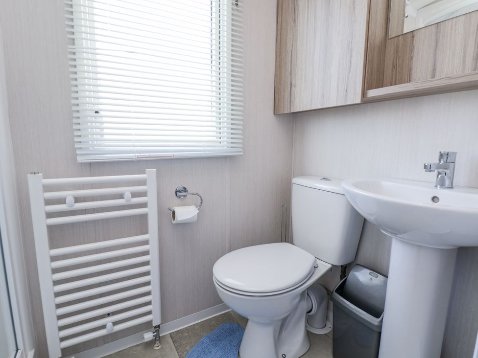 A bathroom with a sink, toilet, and radiator at V9 Ty Mawr Holiday Park