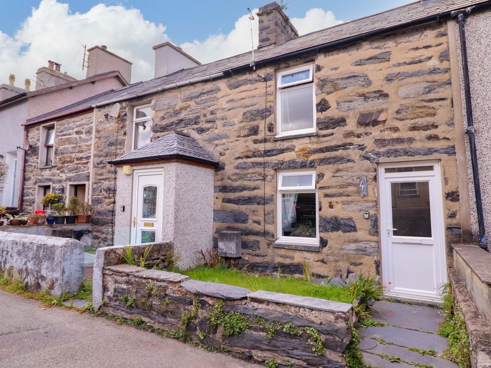 A stone house with a garden and pathway at Bwthynbach in Porthmadog
