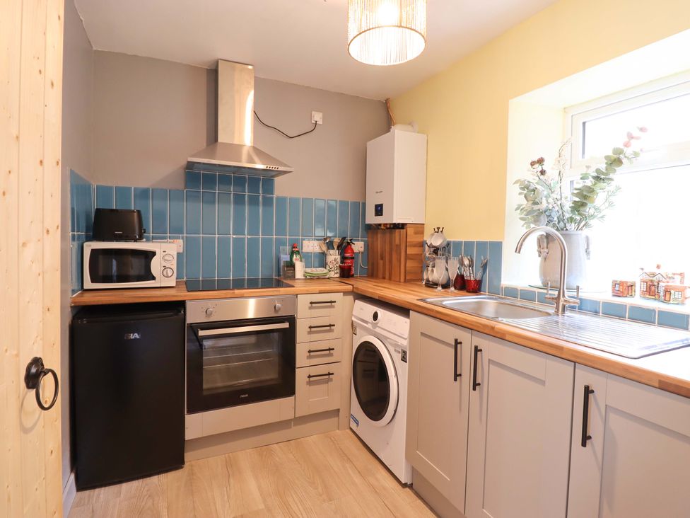 A kitchen with appliances and wooden countertops at Bwthynbach Porthmadog