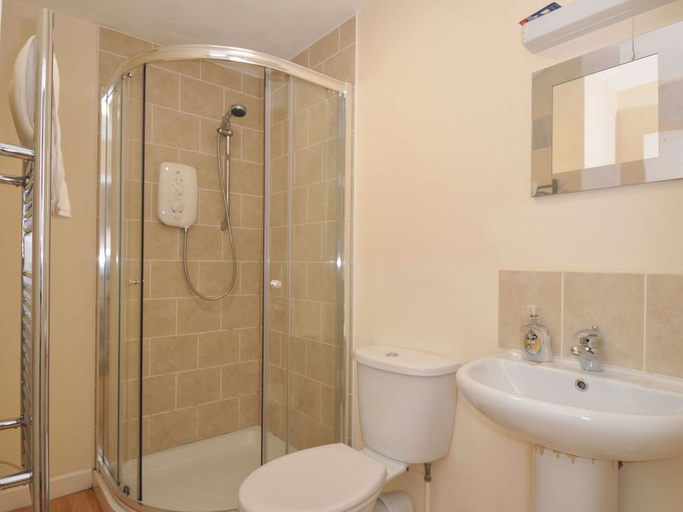 A bathroom with a shower, toilet, and sink at 9 Slipway Cottages, Rock