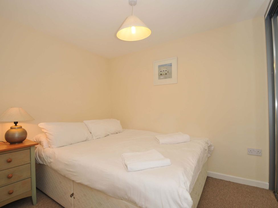A bedroom with a bed and bedside table at 9 Slipway Cottages Rock