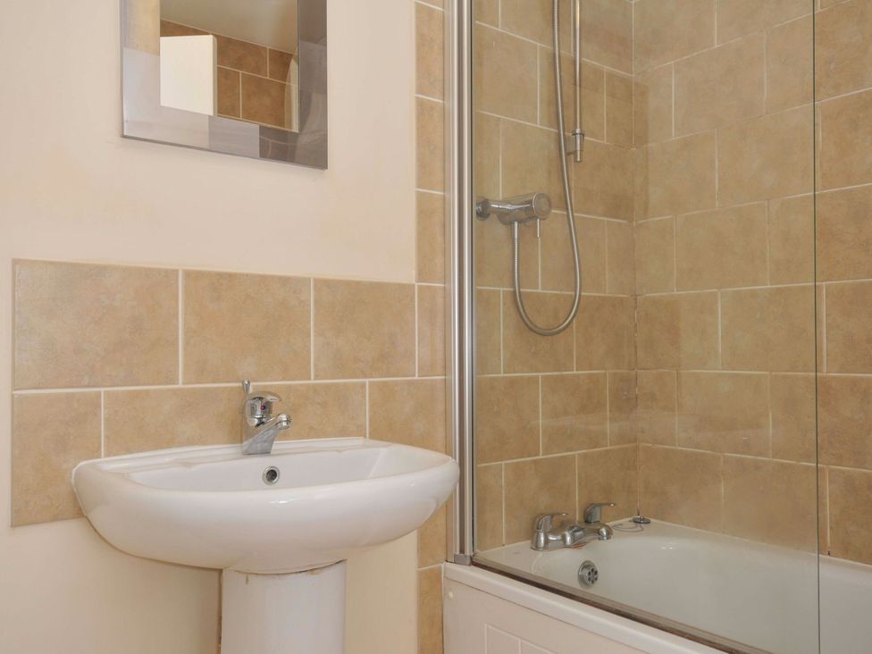 A bathroom with a wash basin and a bathtub at 9 Slipway Cottages in Rock