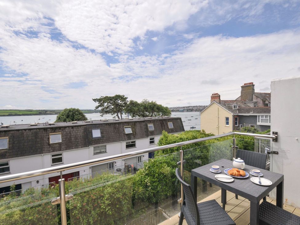 A balcony with a table and chairs overlooking the water at 9 Slipway Cottages in Rock
