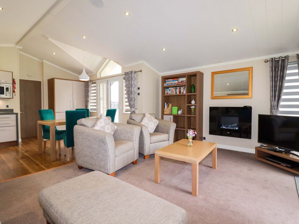 A living room with a sofa and dining area at The Maples 44 St. Austell