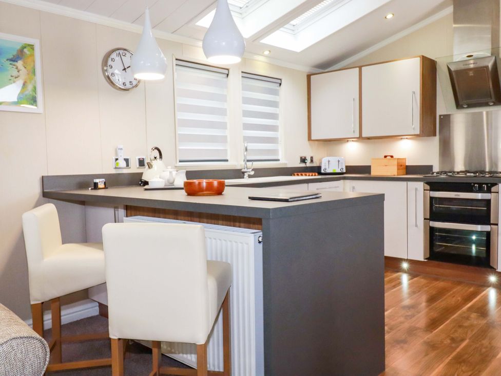 A kitchen with a counter and stools at The Maples 44 St. Austell