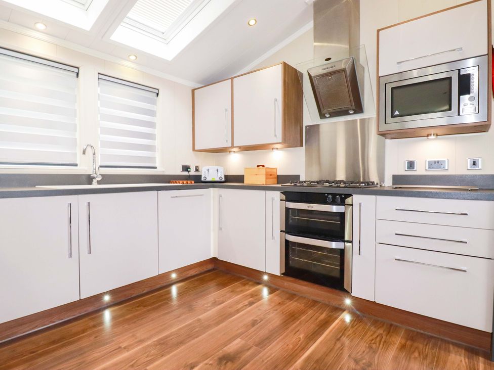 A kitchen with white cabinets and appliances at The Maples 44 in St. Austell