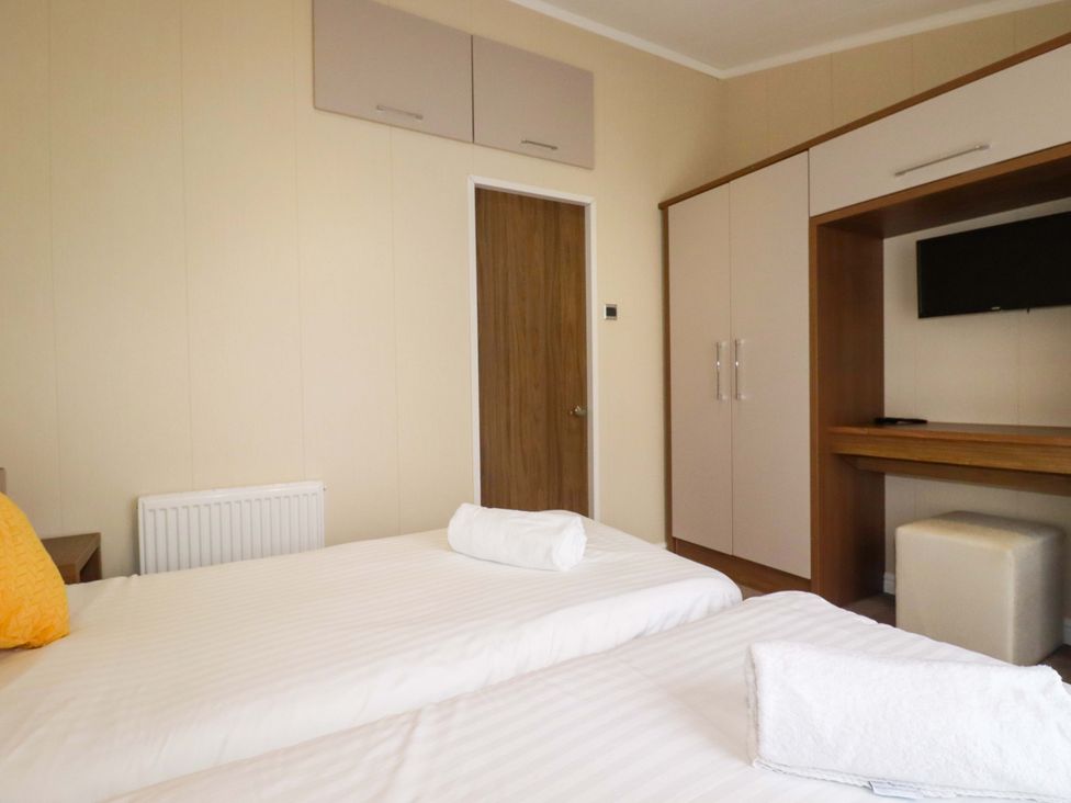 A bedroom with two beds and a television cabinet at The Maples 44 St. Austell