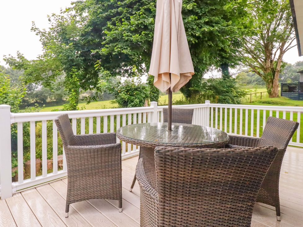 A patio with a table and chairs under an umbrella at The Maples 44 St. Austell
