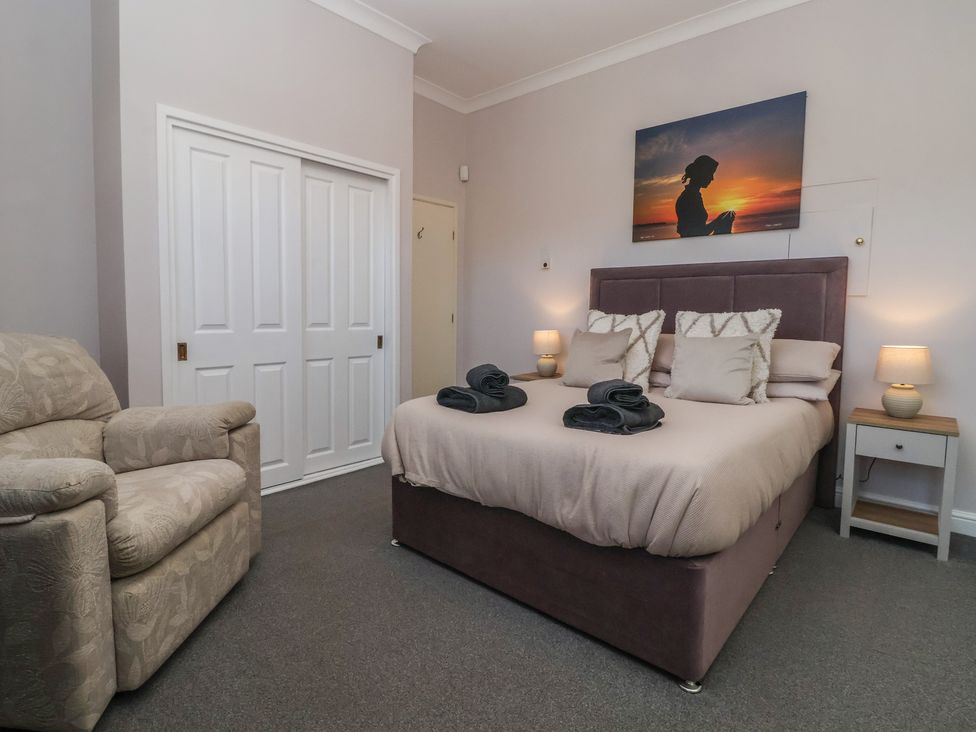 A bedroom with a bed, chair and wardrobe at Sandy Shore in Bridlington