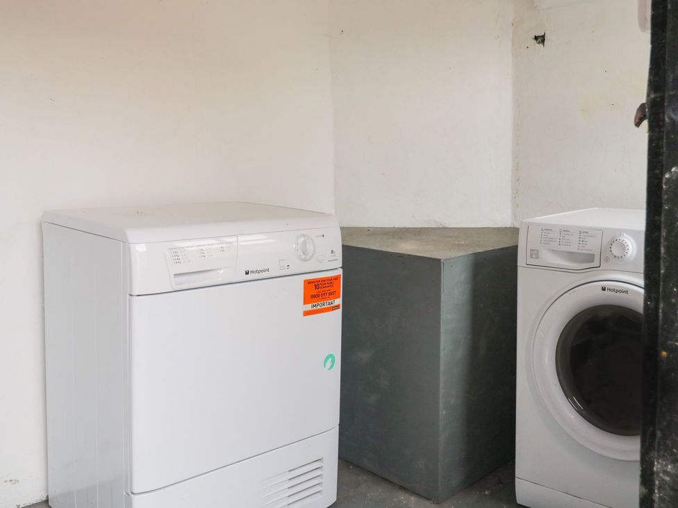 A laundry room with a washer, dryer, and table at Billy's Cottage in Maryport