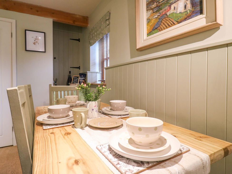 A dining room with a wooden table set for a meal at The Hayloft in Charing