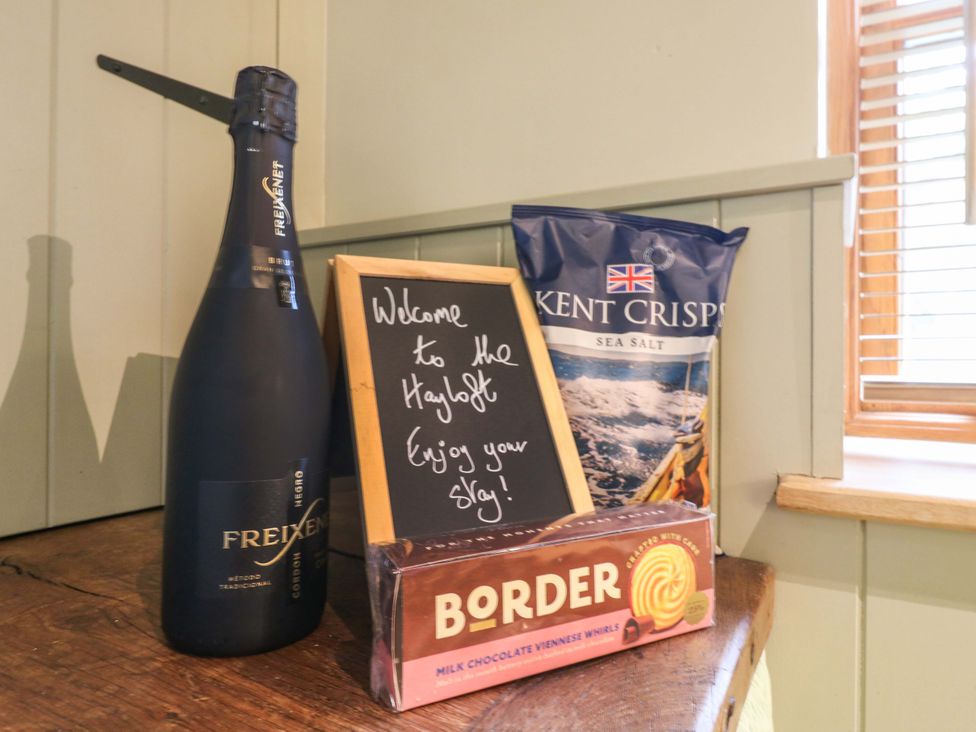 A bottle of champagne, chalkboard, crisps, and biscuits at The Hayloft in Charing