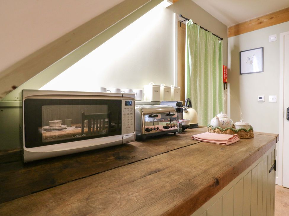 A kitchen with a microwave and toaster on a wooden counter at The Hayloft in Charing