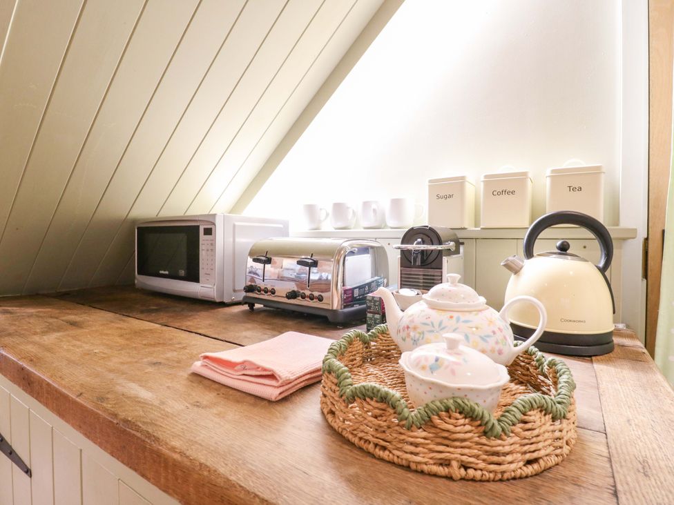 A kitchen with a microwave, toaster, kettle, and tea set at The Hayloft Charing
