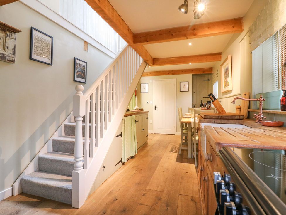 A kitchen with a staircase and dining area at The Hayloft in Charing
