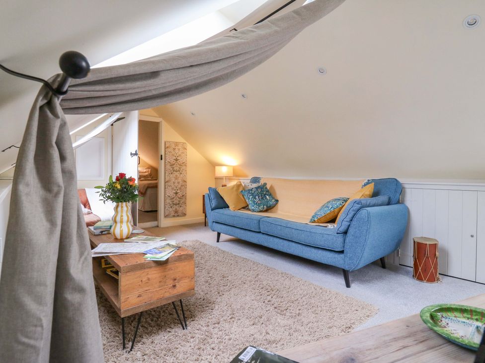 A living room with a blue sofa and coffee table at The Hayloft in Charing