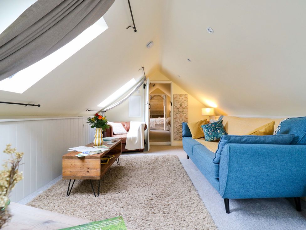 A living room with a sofa, armchair, and coffee table at The Hayloft in Charing