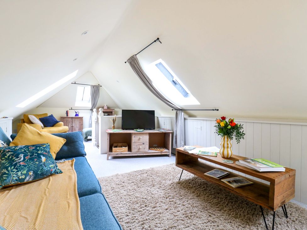 A living room with a sofa and television at The Hayloft in Charing