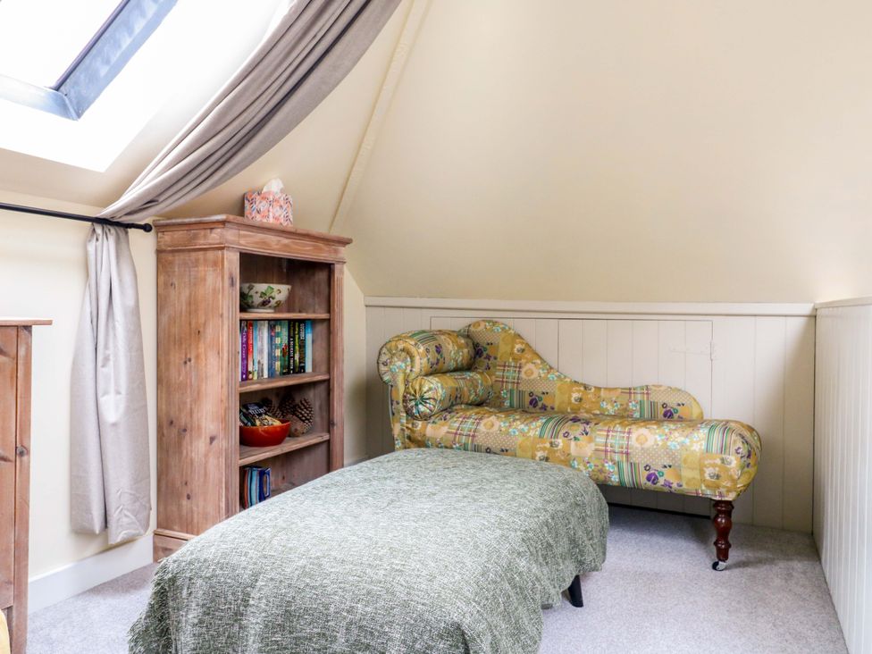 An attic with a bookshelf and a chaise lounge at The Hayloft Charing