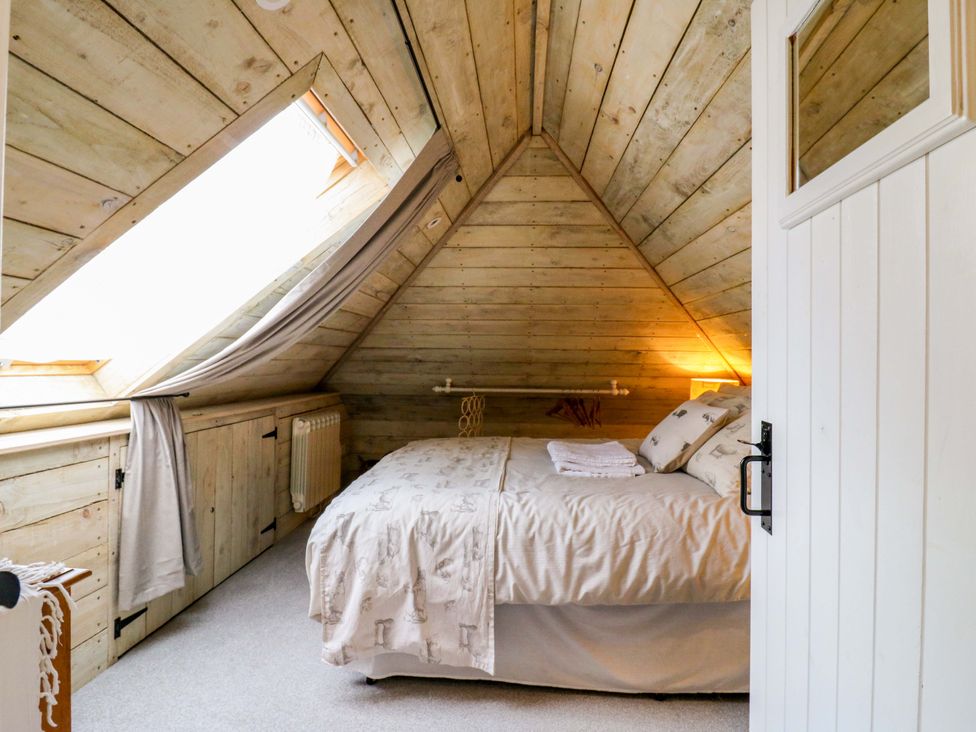 A bedroom with a bed and windows at The Hayloft in Charing