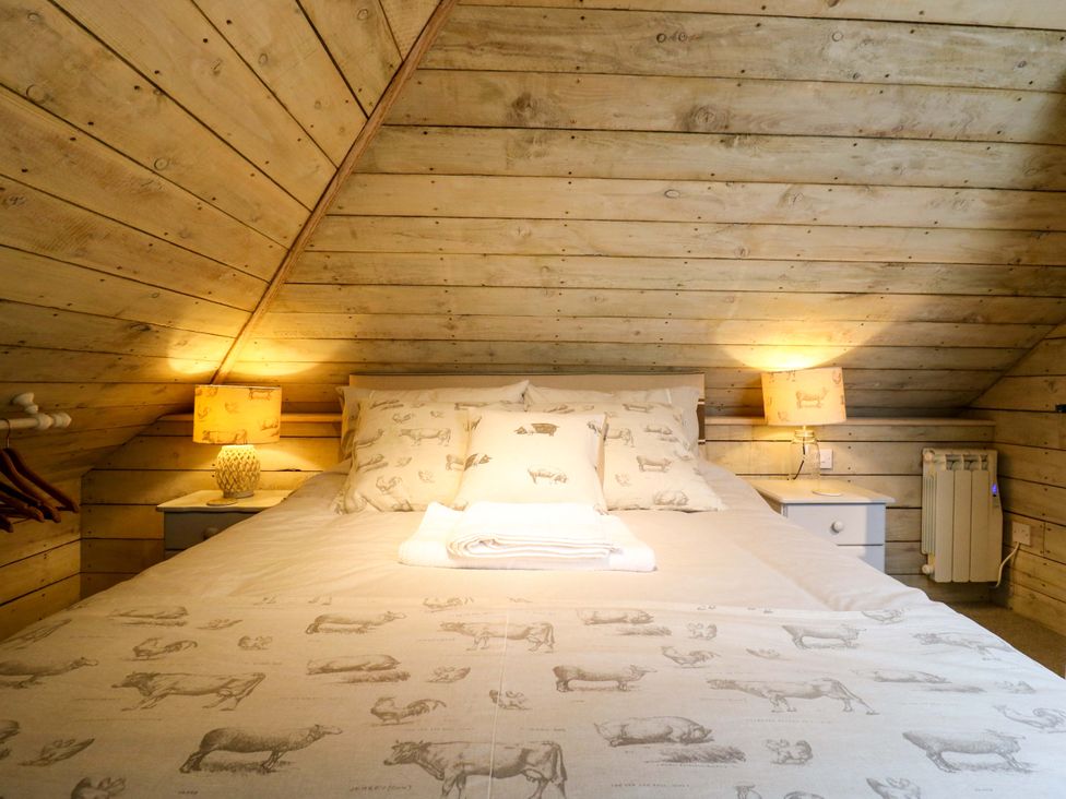 A bedroom with a large bed and lamps at The Hayloft in Charing