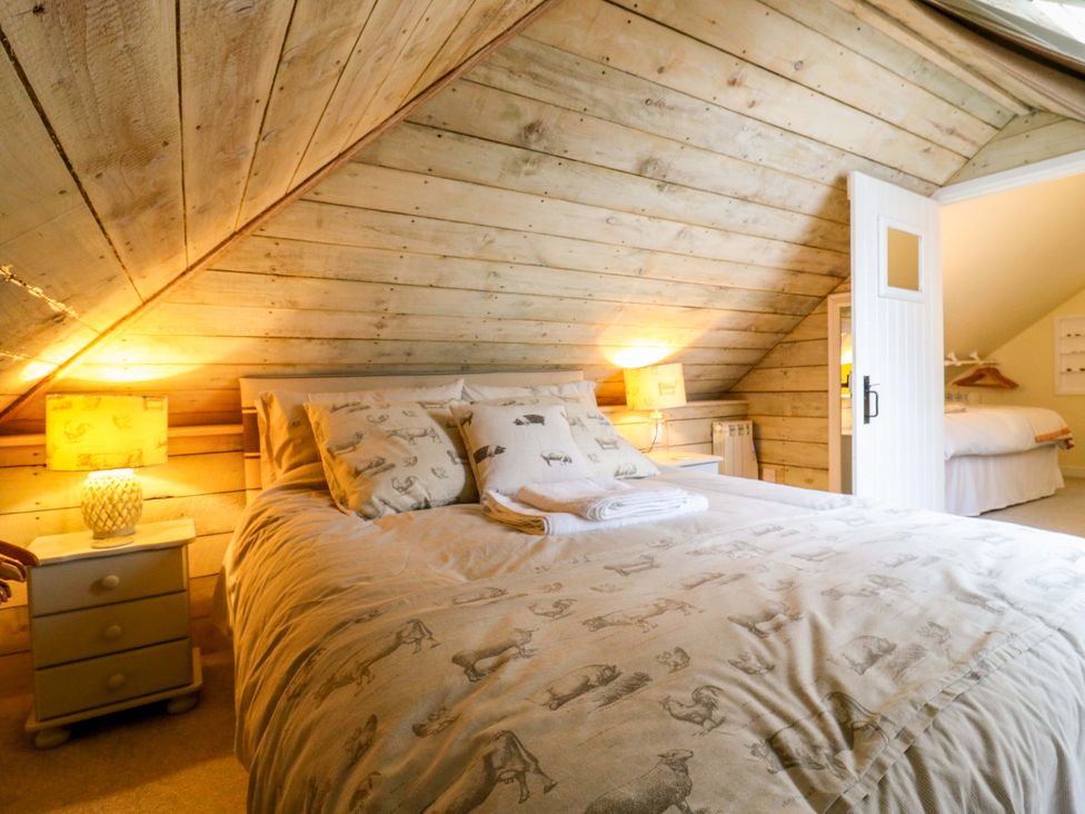 A bedroom with a bed and a doorway at The Hayloft in Charing