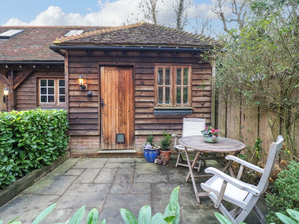 A wooden door and window on a garden area with a table and chairs at The Hayloft in Charing