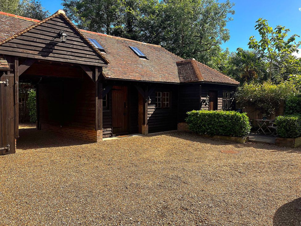 An outdoor area with a wooden building and surrounding plants at The Hayloft - Beautiful Barn Stay in Charing